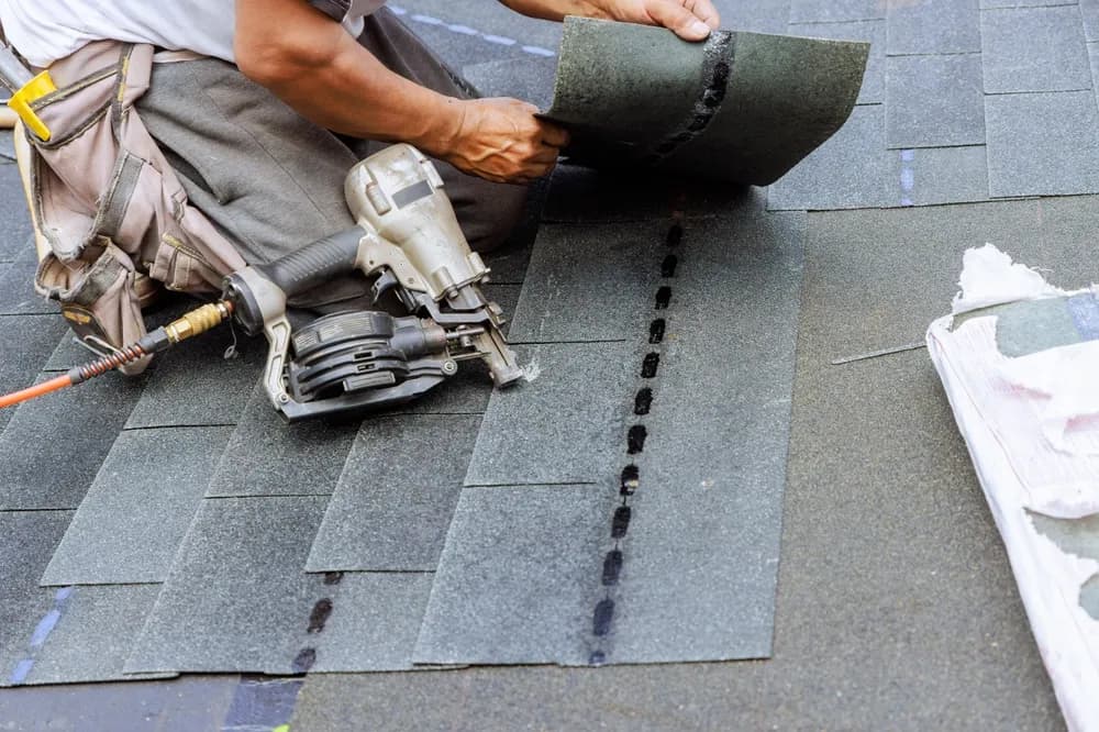 Worker repairing roof shingles